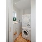 Waschmaschine und Trockner stehen in einem kleinen Raum mit Fenster und Schrank.