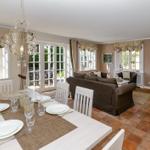 Esszimmer mit Esstisch und Sitzgelegenheiten. Durchgang zum Wohnzimmer mit Sofa und TV.