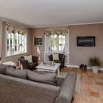 Wohnzimmer mit Sofa, Sesseln, Fernseher und Kamin