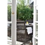 Durch offene Tür blickt man auf einen Außenbereich mit Rattanmöbeln und einem Tisch.