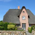 Rotes Backsteingebäude mit strohgedecktem Dach und Garten