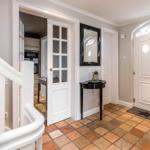 Eingang mit Terrakottboden, weißen Türen und Spiegel an der Wand.