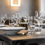 Gedeckter Esstisch mit Gläsern und Tellern.