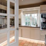 Küche mit weißen Schränken, Edelstahlgeräten und Terrakottaboden