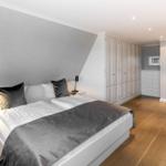 Schlafzimmer mit Doppelbett, Kleiderschrank und Holzboden.