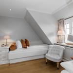 Schlafzimmer mit Dachschrägen, Bett, Stuhl und Fenster.