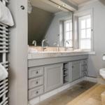 Badezimmer mit Doppelwaschbecken, Spiegelschrank und Heizkörper