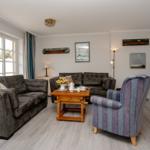 Wohnzimmer mit zwei Sofas, einem Sessel und einem Fernseher.