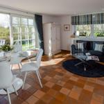 Ein Esszimmer mit Tisch und Stühlen, ein Wohnbereich mit Sofa und Couch, Terrasse mit Blick auf Garten.