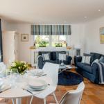 Essbereich mit Tisch und Stühlen. Wohnbereich mit Sofa und Fenster.