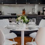 Runder Tisch mit weißen Stühlen und Geschirr in moderner Küche.