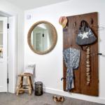 Eingangsbereich mit Spiegel, Stuhl und Holzpaneel mit Kleidung.