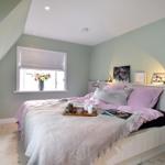 Schlafzimmer mit Bett, Fenster und Fernseher an der Wand.