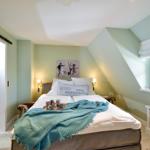 Schlafzimmer mit Dachschrägen, Bett, Fenster und Schiebetür.