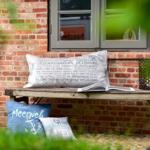 Bank vor Backsteinmauer mit Kissen und offenem Buch.