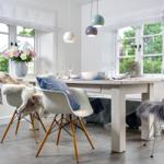 Esszimmer mit Tisch, Stühlen und Fenstern mit Blick auf Grün.