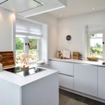 Moderne Küche mit weißen Schränken, Fenstern und Kücheninsel.