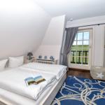 Schlafzimmer mit Doppelbett, Blick auf grünes Feld durch Fenster.