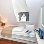 Schlafzimmer mit Dachschrägen, Bett, Fenster und Spiegel.