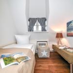 Ein Schlafzimmer mit Bett, Fenster, Lampe und Wandbild.