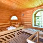 Holzsauna mit Sitzbänken, Fenster und Holzbadewanne.