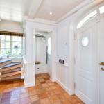 Haus mit Eingangstür, Flur und Treppe mit Holzstufen und Terrakottboden.