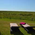 Zwei Liegestühle auf einer Wiese mit Blick auf eine grüne Landschaft.