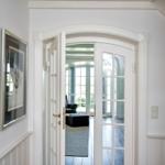 Durchgehend weißer Flur mit Tür zum Wohnbereich. Blick auf Sitzgelegenheit und Fenster.