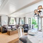 Wohn- und Essbereich mit Sofa, Tisch und Kronleuchter.