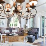 Wohn- und Essbereich mit Sofa, Stuhl und Kronleuchter. Durchgang zur Terrasse mit Garten.