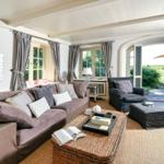 Wohnzimmer mit Sofa, Sessel und Blick auf Garten.