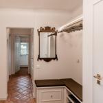 Entrance area with closet, mirror, and picture on the wall. Hallway leads to the kitchen.