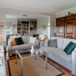 Living room with two sofas, coffee table, and wooden cabinet. Passage to library with bookshelves.