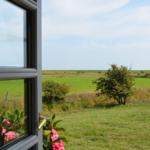 View through the window shows a green meadow with trees and a clear sky.