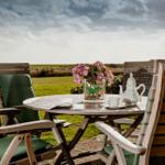 Wooden table with chairs, flowers, and tea service in the garden.