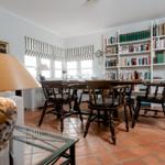 Dining room with wooden table, chairs, and bookshelf against the wall.