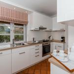 Kitchen with white cabinets, wooden surfaces, and red window shade.