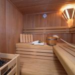 Sauna mit Holzbank, Körbchen und Thermometer an der Wand.