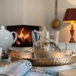 Tisch mit Teekanne, Kerzen und Meeresdekoration vor Kamin