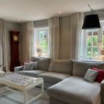 Wohnzimmer mit grauem Sofa, weißem Tisch und hängender Lampe.