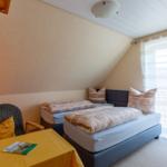Zimmer mit Doppelbett, Fenster und Schreibtisch mit Stuhl.