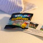 Sour Glowworms Minis und eine Karte mit Ferienhausinformationen liegen auf einer Oberfläche.