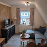 Wohnzimmer mit Sofa, TV und Fenster mit Blick auf Gebäude.