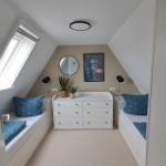 Zimmer mit zwei Schlafcouchen, weißen Schränken und Dachschrägen.