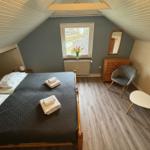 Schlafzimmer mit Dachschräge, Bett, Stuhl und Fenster.