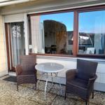 Terrasse mit zwei Stühlen und Tisch vor Fenster und Glastür