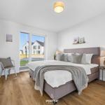 Schlafzimmer mit Bett, TV und Fensterblick auf Haus