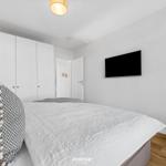 Schlafzimmer mit Bett, Kleiderschrank, Fernseher und Stuhl.