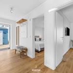 Haus mit Eingangsbereich, Schlafzimmer und Wohnbereich mit Holzboden und weißen Wänden.