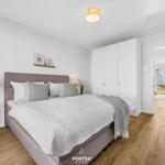 Schlafzimmer mit Bett, Kleiderschrank und Holzboden. Durchgang zum Wohnbereich.
